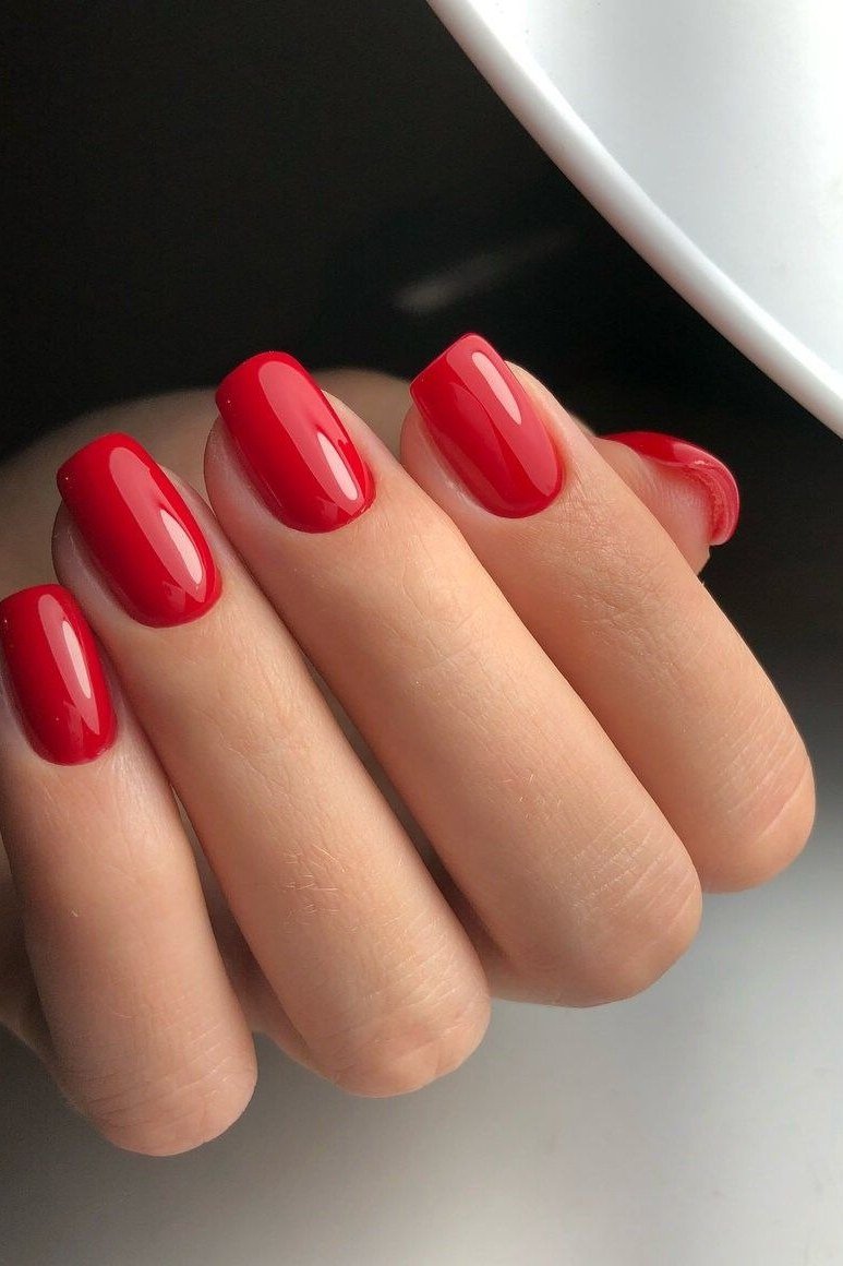 Glossy classic red short almond nails, clean white background, sophisticated nail design for women over 50