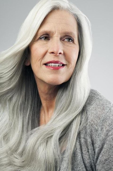 long silver grey hair on smiling woman over 60, front view