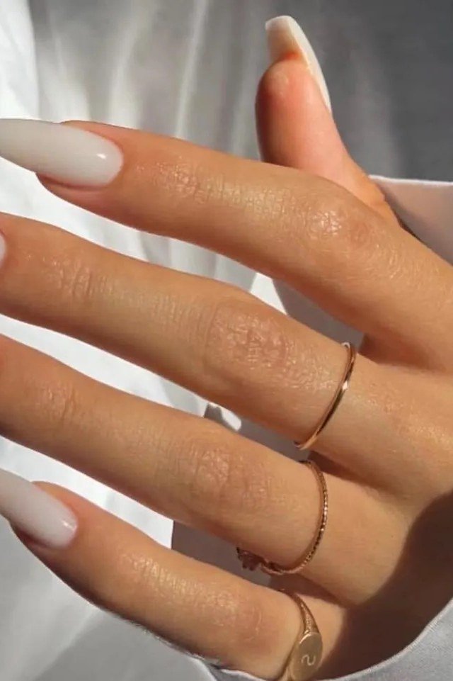 Milky white square nails with gold rings on an elegant hand