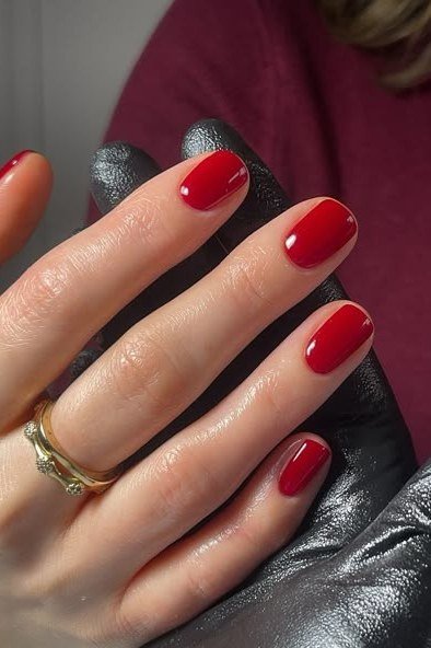 Deep red almond nails with gold ring, maroon sleeve, sophisticated nail design for women over 50