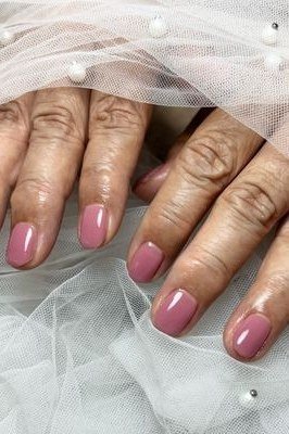 Glossy pink short nails on older hands, best manicure idea for women over 60