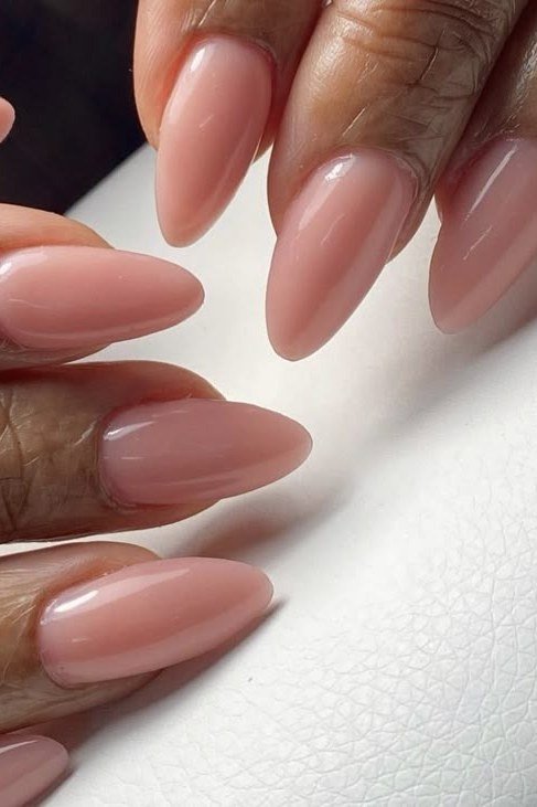 Glossy nude almond nails, close-up on dark skin hand - classy nail design for older women