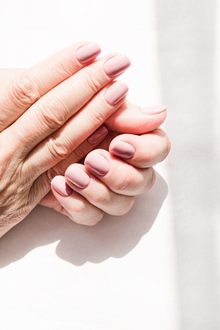 Hydrated mature hands with soft mauve manicured nails