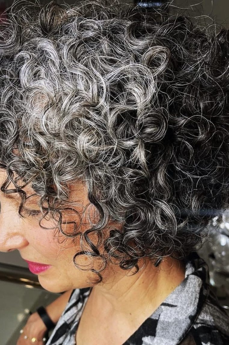 Voluminous silver grey tight curly bixie haircut side view for women over 60