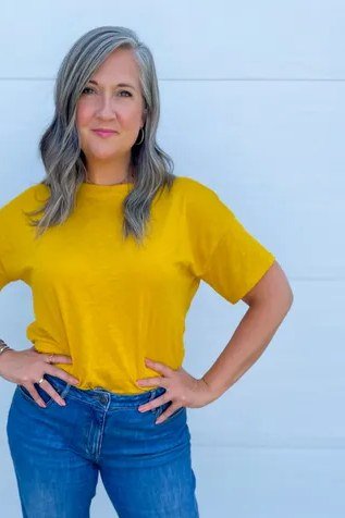 Woman over 50 wearing mustard tee with blue jeans, everyday casual outfit idea