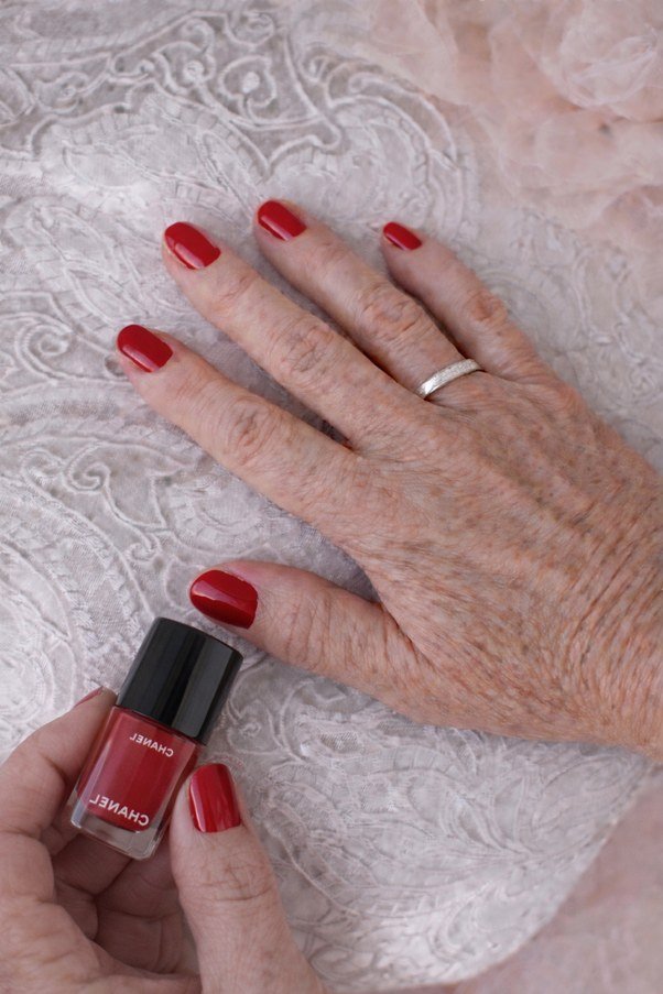bright red nails next to Chanel polish bottle