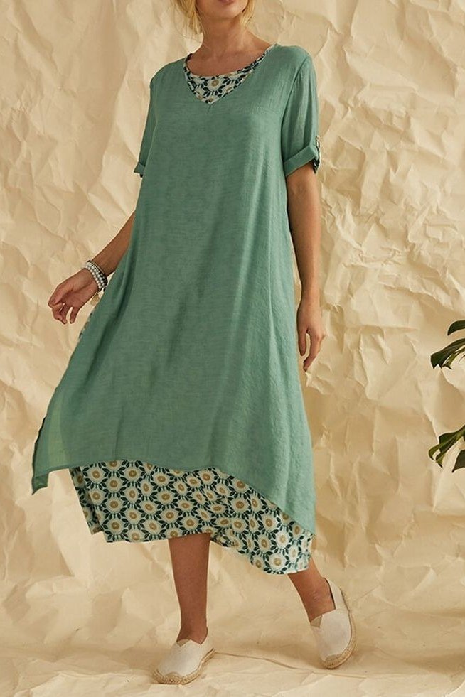 Mature woman in a loose sage-green tunic dress with a green floral hem panel and elbow sleeves, studio shot - summer dress for women over 50