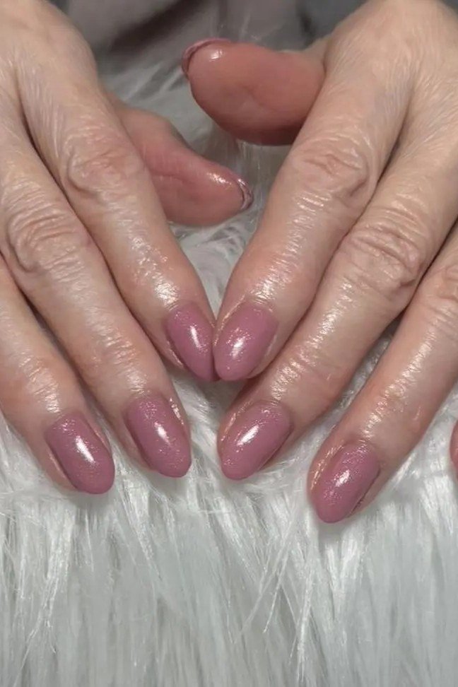 Dusty rose short nails, both hands on white fur, best manicure idea for women over 60