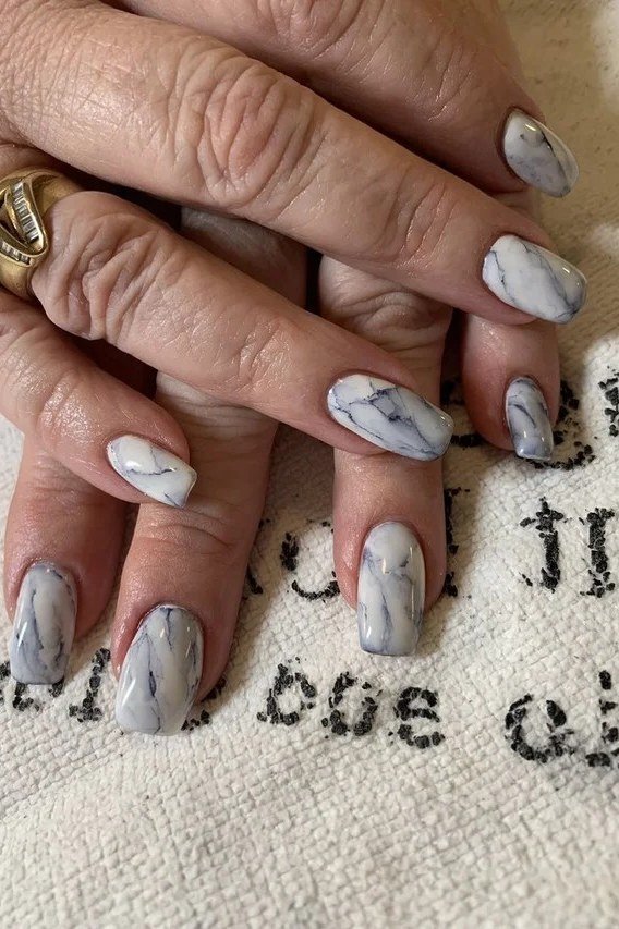 Nail art design for women over 60: grey marble nails on mature hands