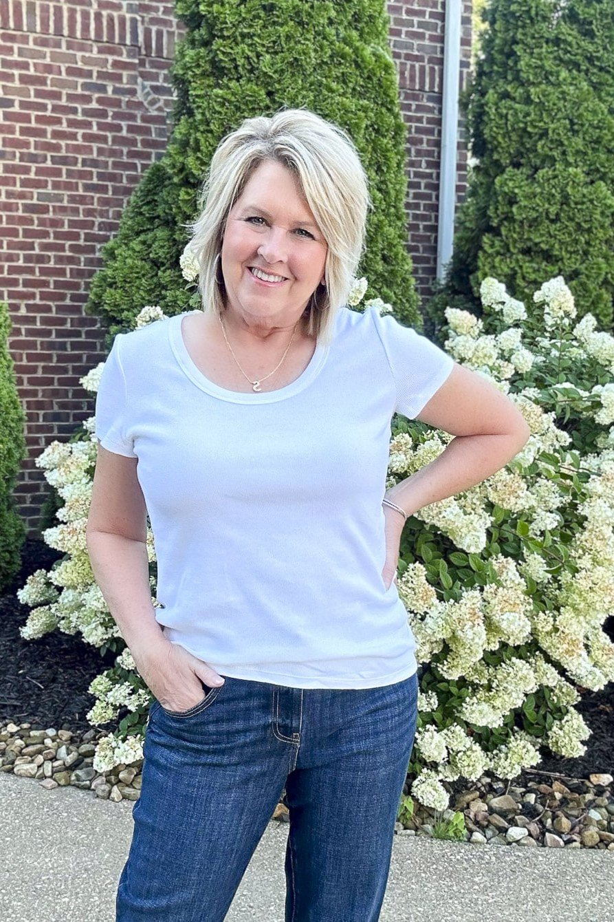 Woman over 50 wearing white v-neck tee with medium jeans, everyday casual outfit idea