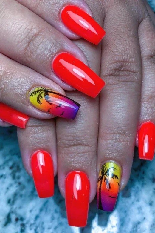 Cherry Red Nails with Sunset Palm Accents - Glossy cherry red covers most nails here, while two accent nails show a tiny sunset with palm silhouettes in orange and purple. The medium coffin shape keeps the look modern.