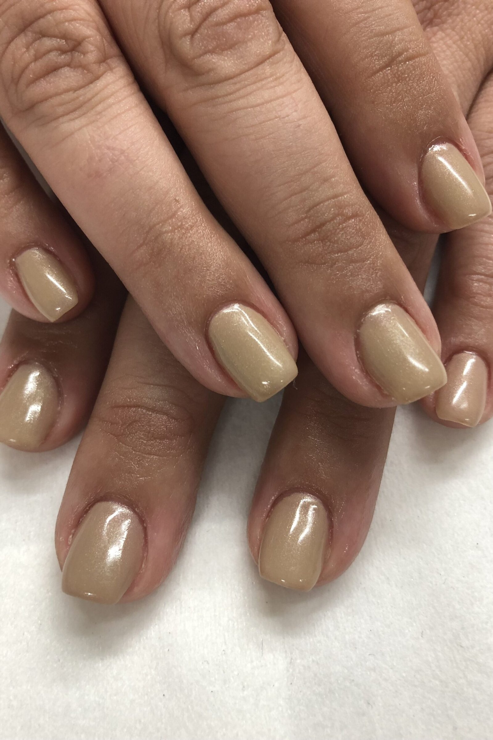 Warm nude short nails on mature brown hands