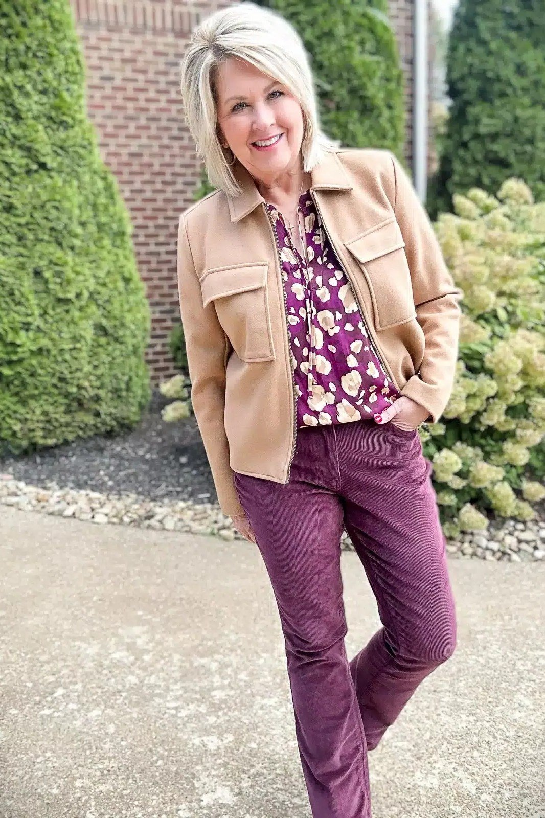 Tan suede trucker jacket with purple floral blouse and purple jeans