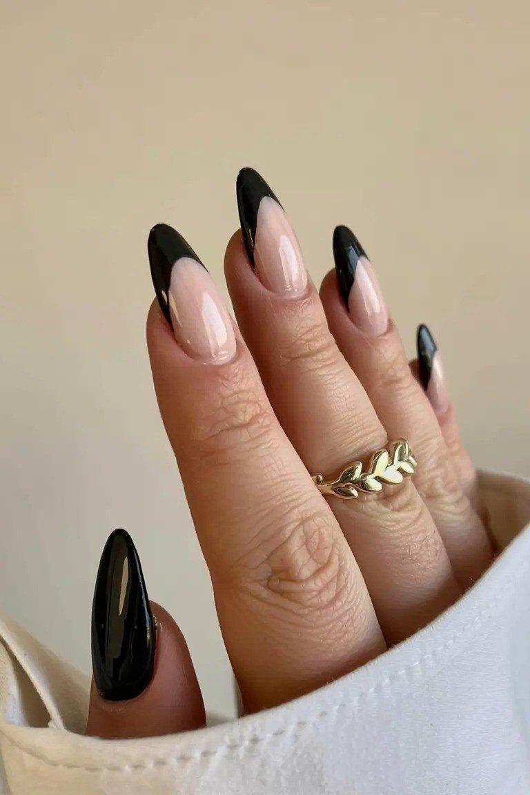 Black French tip almond gel nails with gold ring, edgy fall manicure for mature hands