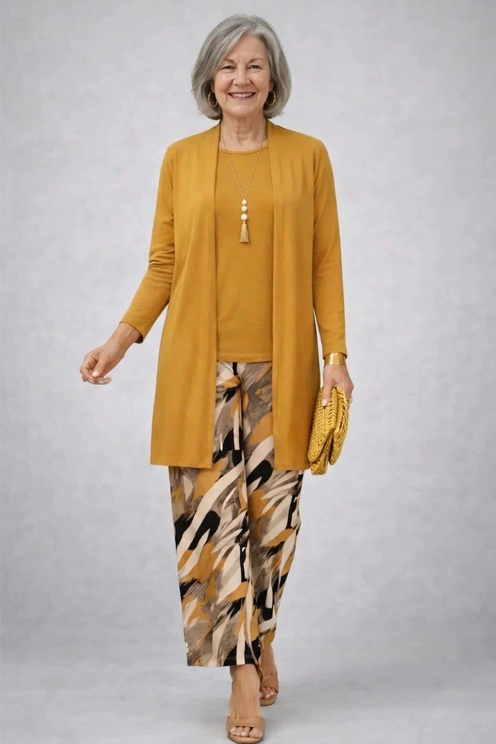 Woman over 60 in a mustard yellow cardigan set with patterned palazzo pants