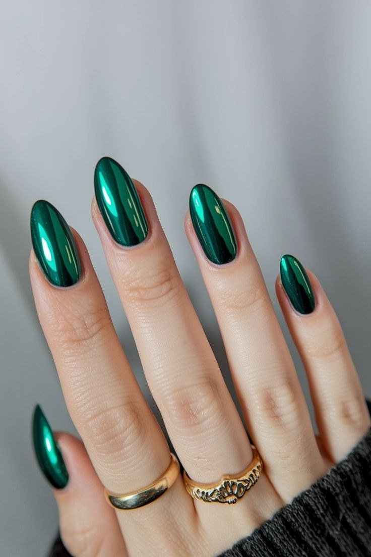 Emerald green chrome gel nails on almond shape with gold rings, fall metallic nails