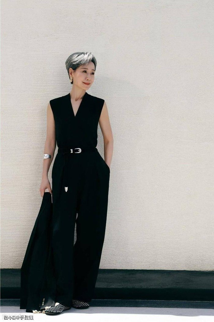 Older woman in black sleeveless belted jumpsuit