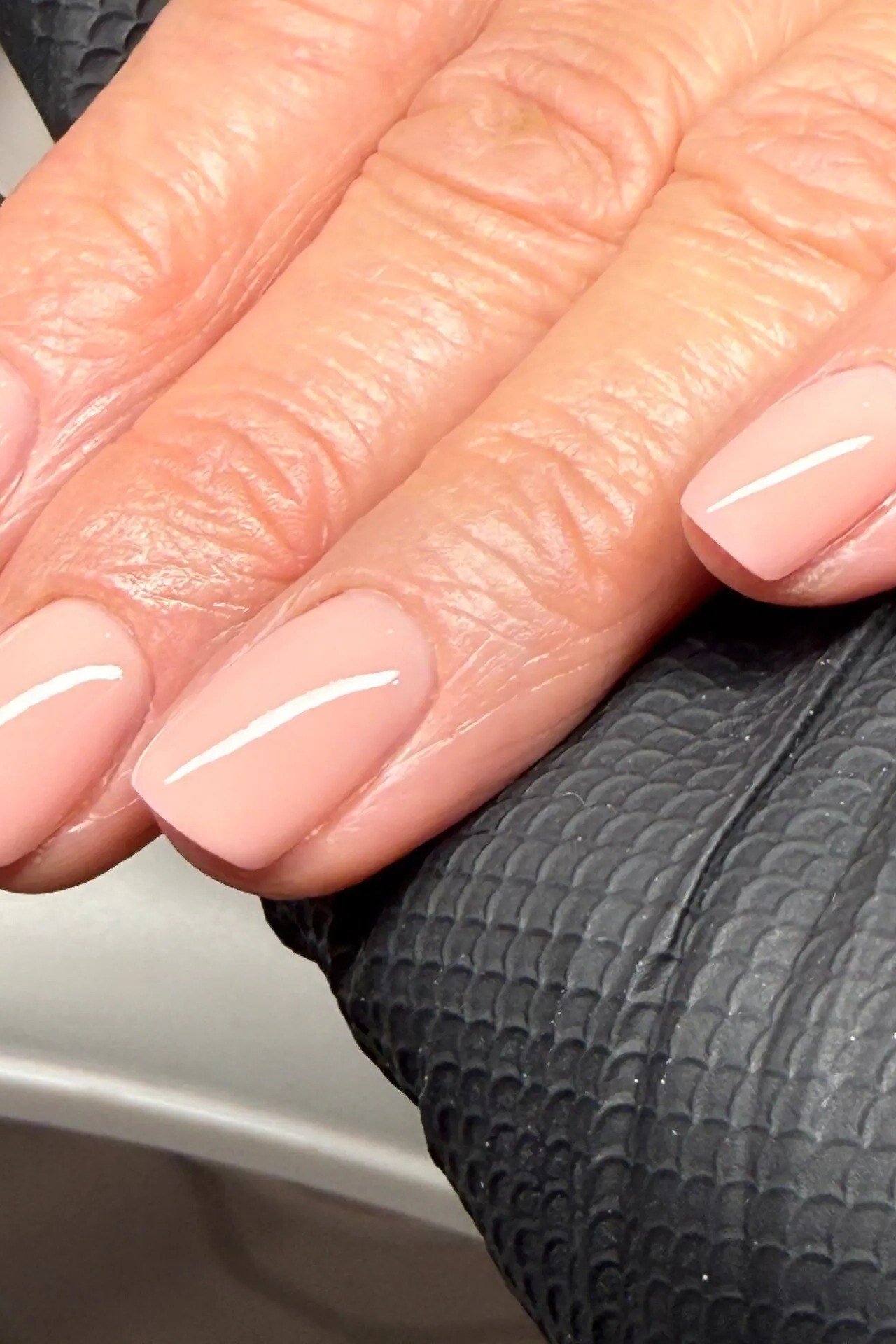 Warm Nude Squoval on the Armrest - short nude nail idea for women over 50