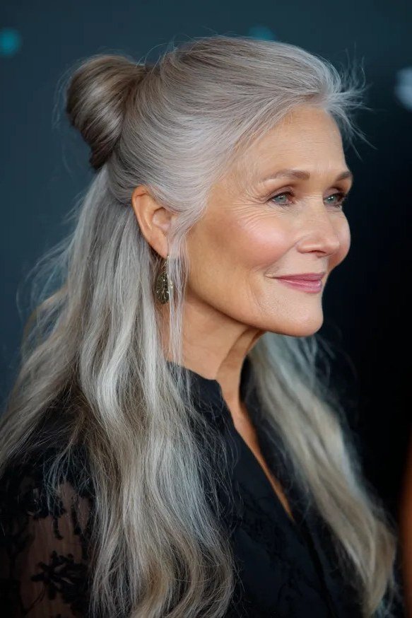 Long silver-gray hair with small top bun and loose waves for women over 50