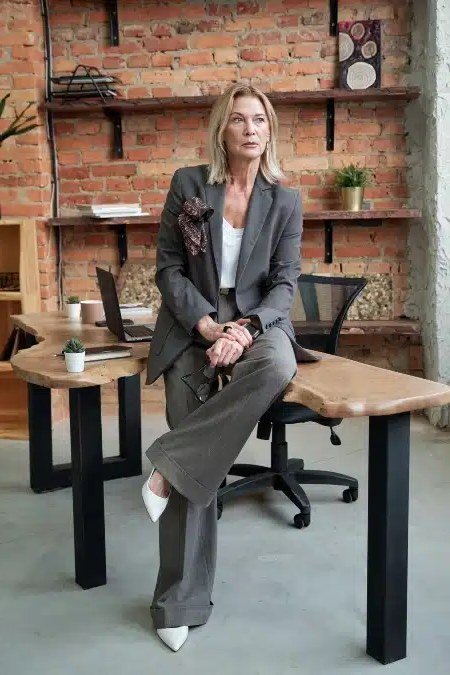 Work outfit for women over 40: gray blazer with wide-leg trousers at a desk
