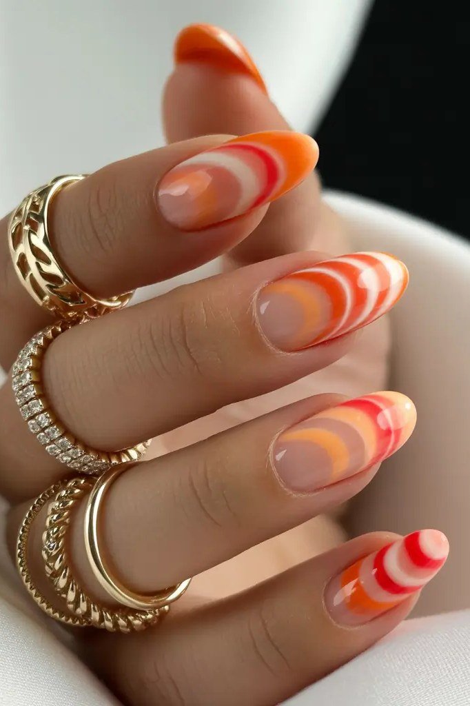 Orange and coral swirl marble design, almond shape, medium length, glossy, gold rings, fall nail color for women over 40