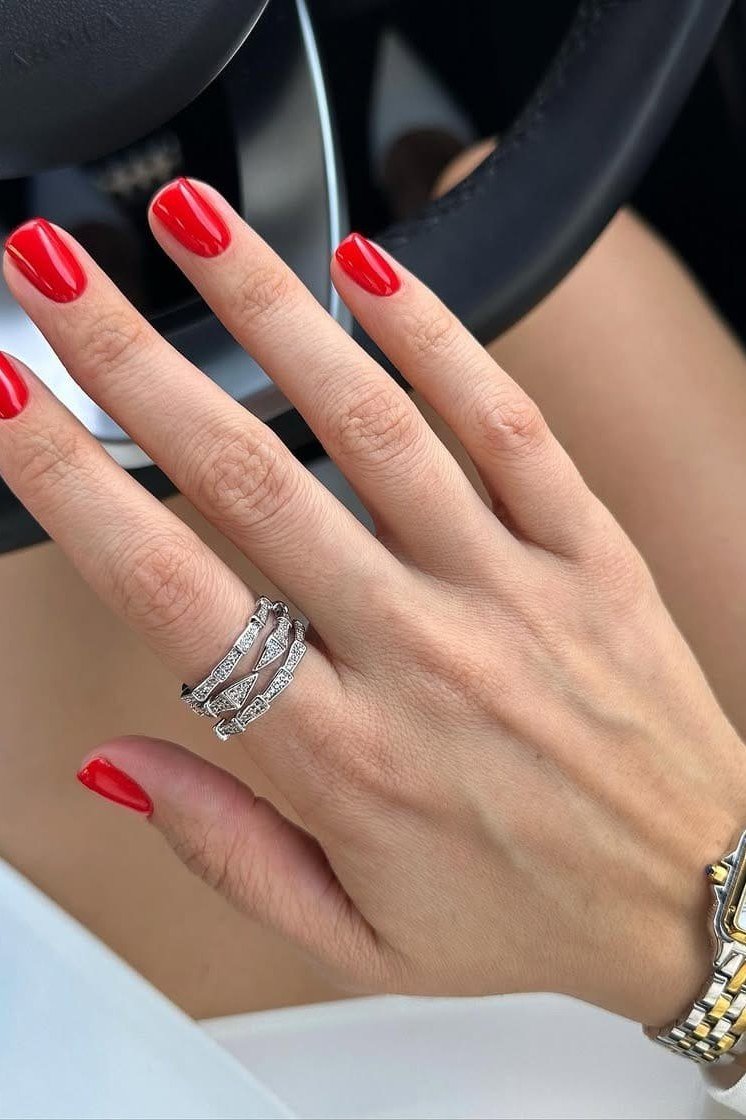 Classic red nails on steering wheel with gold watch, sophisticated nail design for women over 50