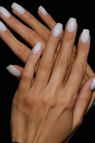 Milky white short oval nails against a black background