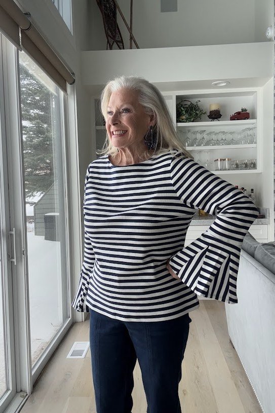 Woman over 50 wearing bell-sleeve striped top with dark jeans, everyday casual outfit idea