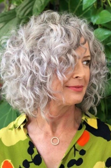 Tousled silver shag curly lob on woman over 60, outdoor