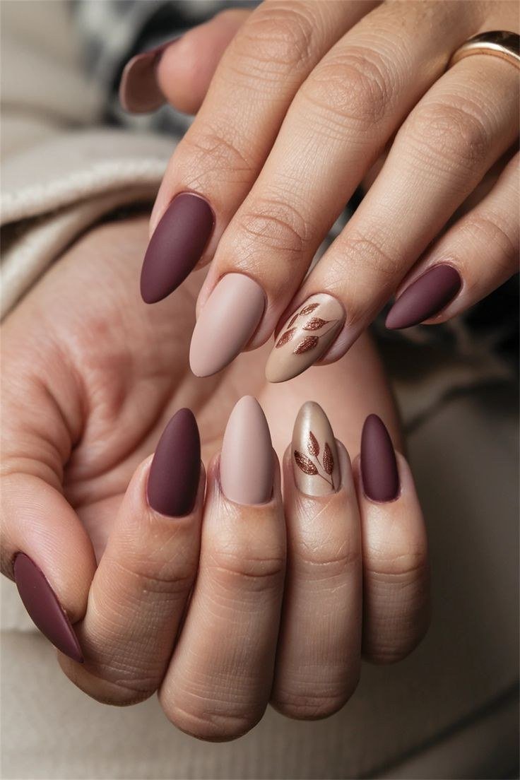 Deep plum solid with subtle gold leaf accents, almond shape, short-medium length, matte finish, fall nail color for women over 40