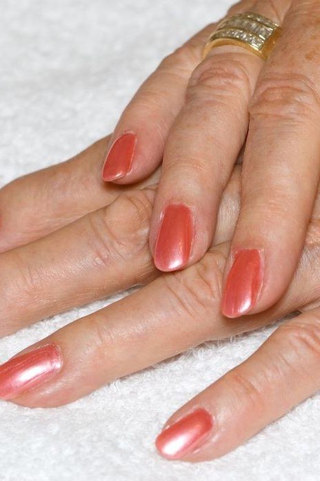 Mature hands with warm coral nail polish