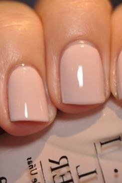 Pale nude nails holding a polish bottle