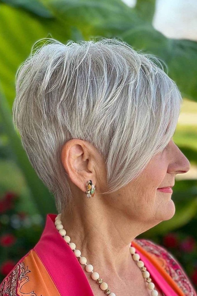 Longer silver pixie haircut tucked behind ear with pearl necklace for women over 60