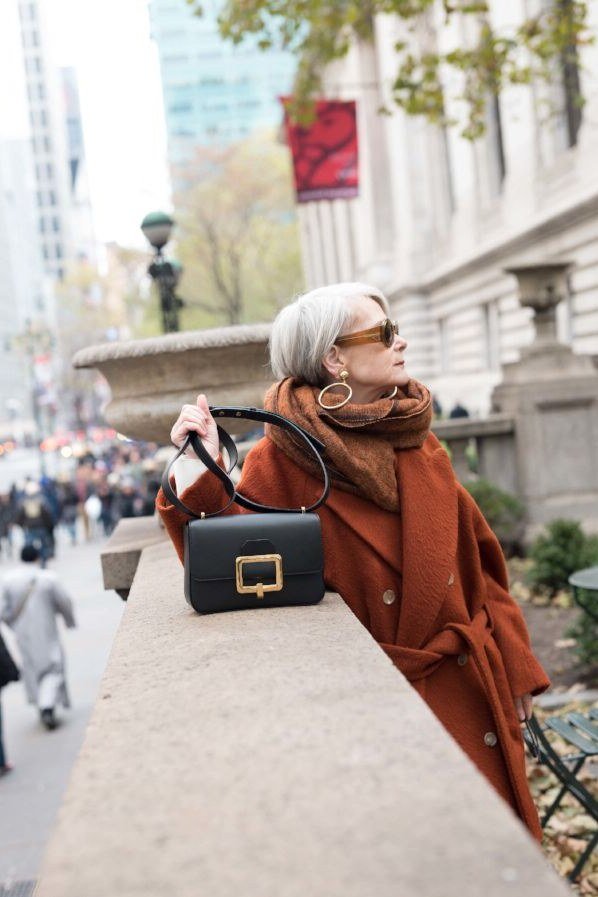 Elegant fall outfit for women over 70: rust poncho with black handbag