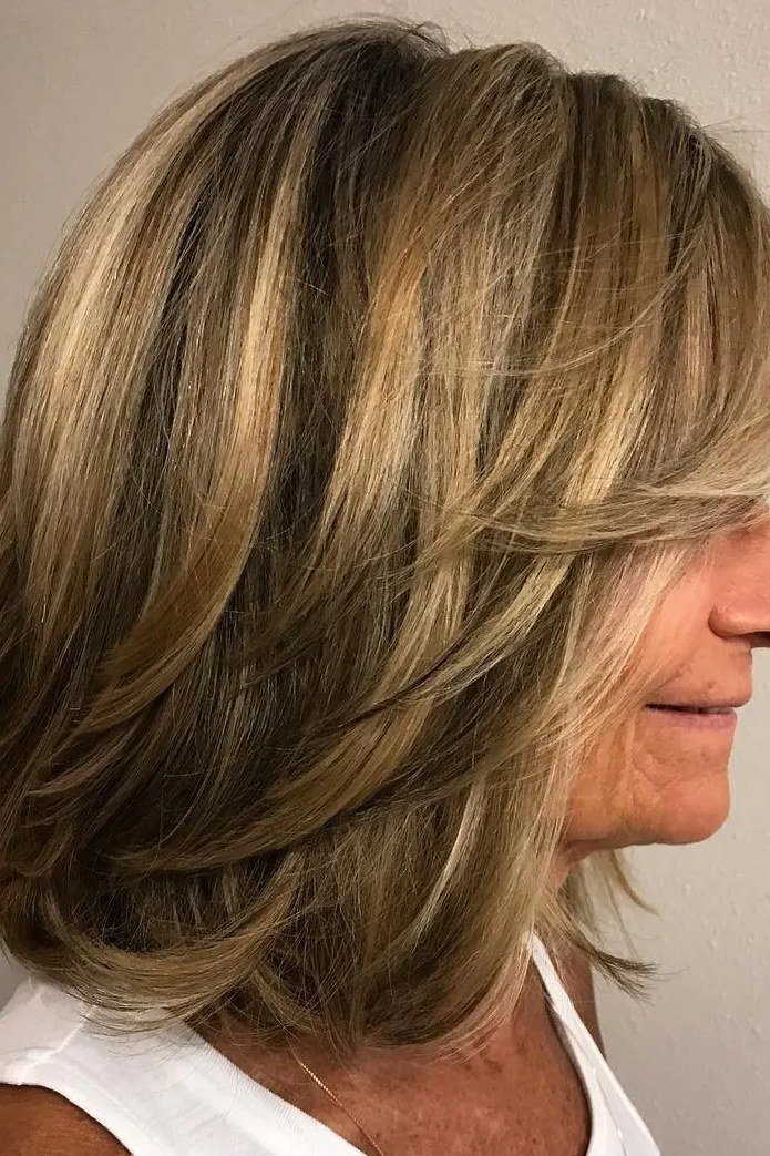 Smooth blonde layered medium-length hairstyle with subtle movement, side view, for women over 50