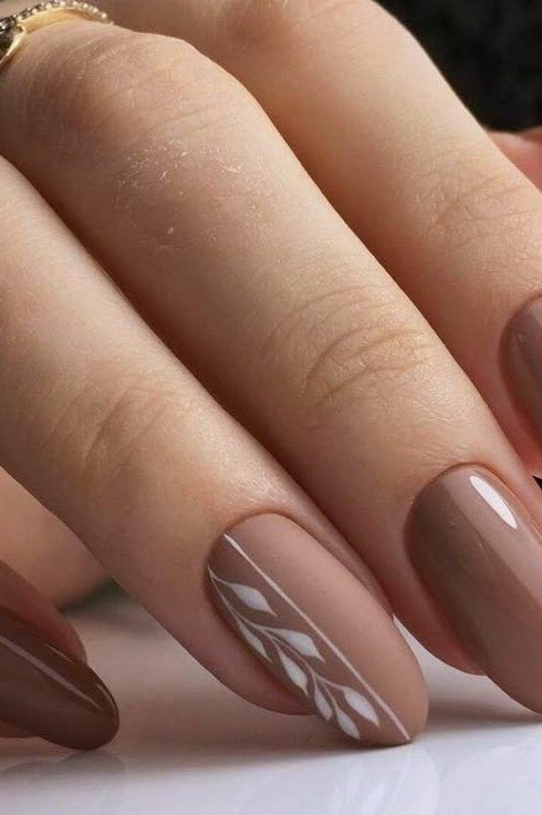 Warm taupe solid with white hand-painted leaf art on two accent nails, almond shape, medium length, glossy, fall nail color for women over 40