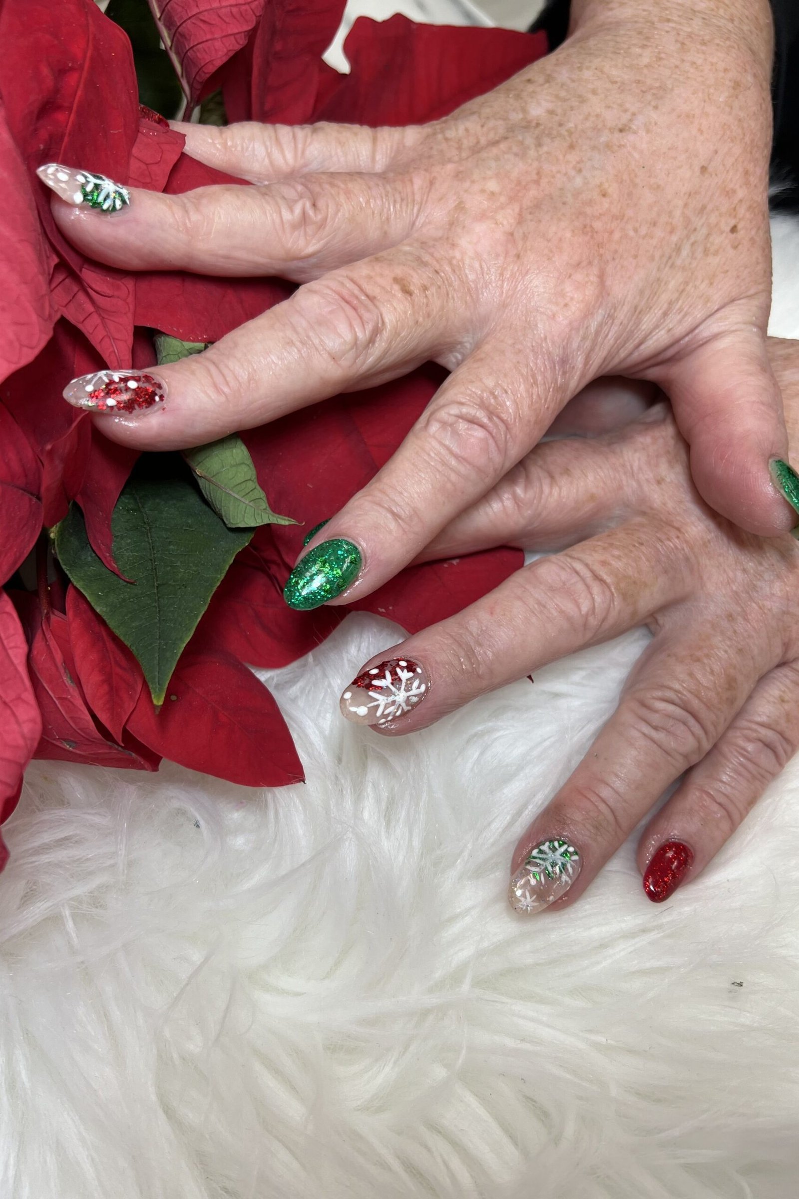 Red and green glitter nails with poinsettia, mature hands - Christmas nail design for older women