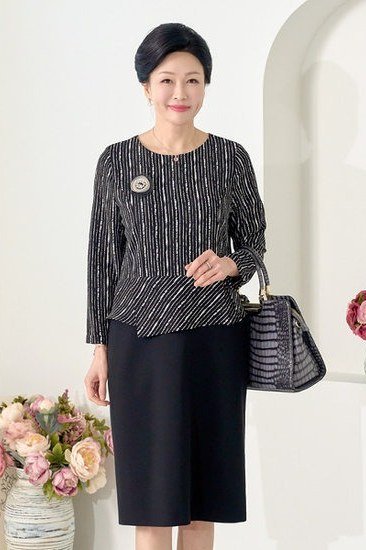 Older woman in black pinstripe peplum jacket and skirt