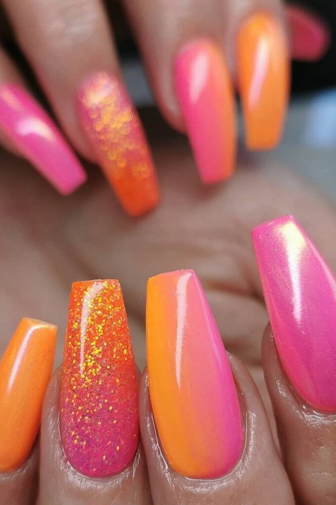 Hot Pink Orange Stiletto Nails with Glitter Accent - Long stiletto nails fade from hot pink to glowing orange, and one accent nail sparkles with orange glitter. The glossy finish keeps the whole look fierce and fun.