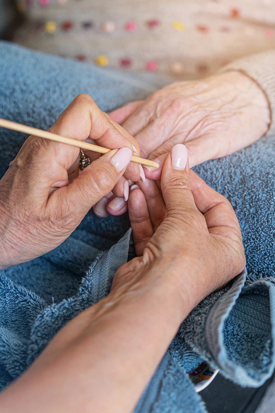 Pushing back cuticles gently with an orangewood stick on mature hands