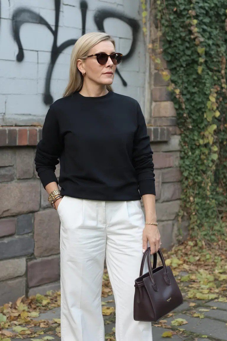 Fall city outfit for women over 50: light gray cardigan white trousers brown bag