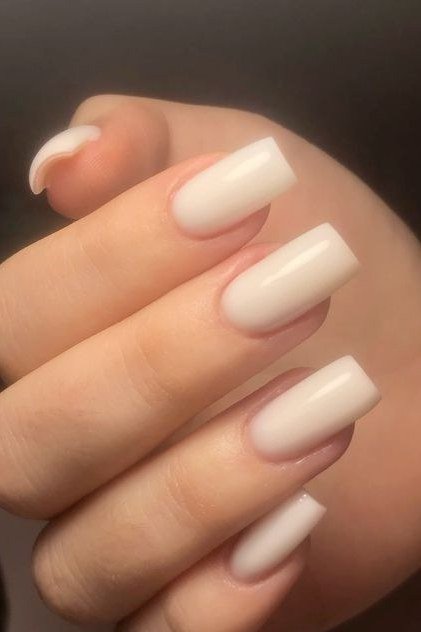 Close up of short milky white nails with glossy finish