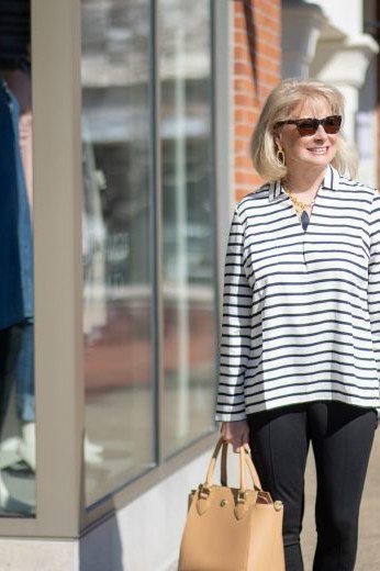 Woman over 50 wearing striped top with black pants and tan tote, everyday casual outfit idea