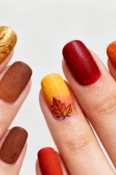 Warm matte fall nails in brown red amber with bronze glitter accent and hand-painted fall leaves for older women