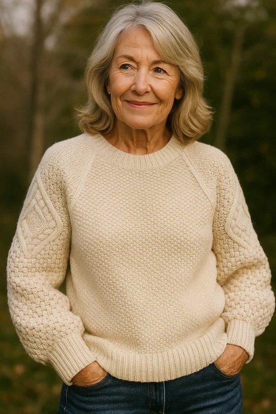 Cream fisherman-knit sweater with dark jeans outdoors, cozy sweater outfit idea for women over 70
