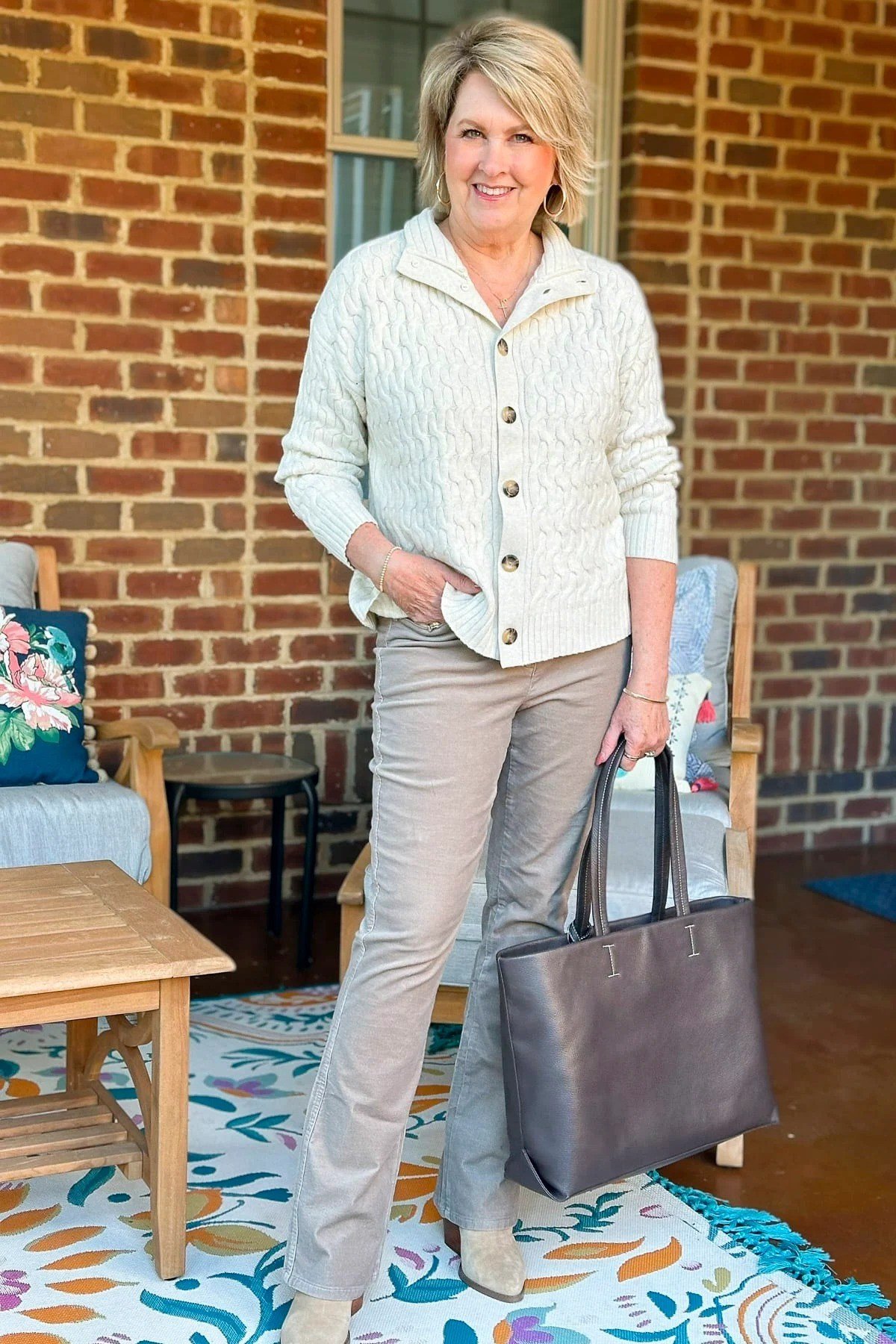 Casual fall outfit for women over 60: cream fisherman knit sweater, relaxed jeans, beige slip-ons