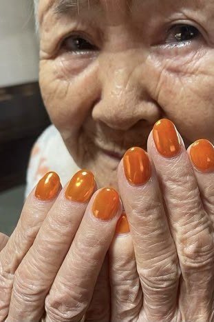 Mature hands with bright orange nail polish