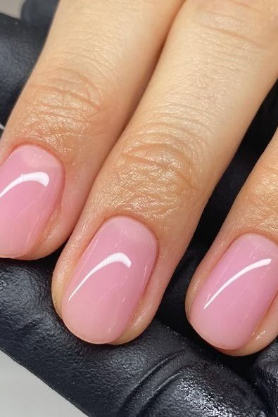 short oval, glossy baby pink, fingers on black glove background , for women over 60