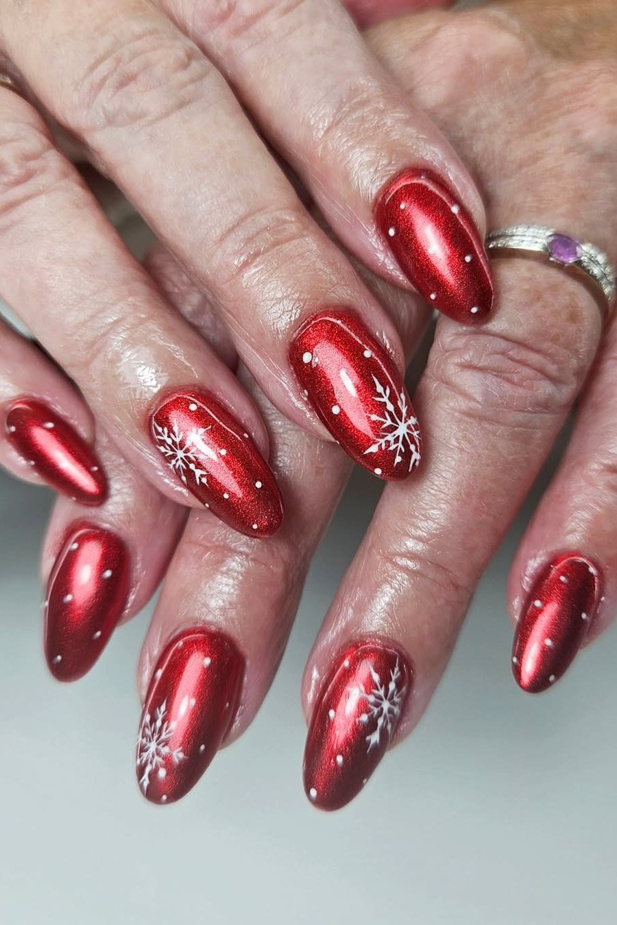Mature hands, metallic red nails with white snowflake art - classy Christmas nail idea for women over 70