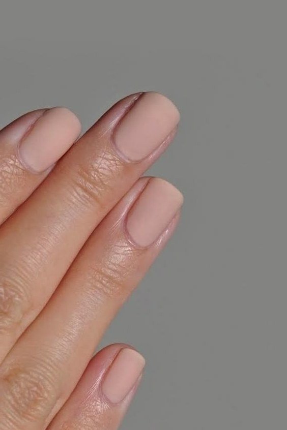 Soft nude nails on grey background